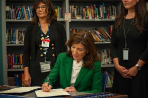 Gov Kathy Hochul sits down to sign one of two bills into law during a visit to Tech Valley High School on Thursday, Sept. 7.