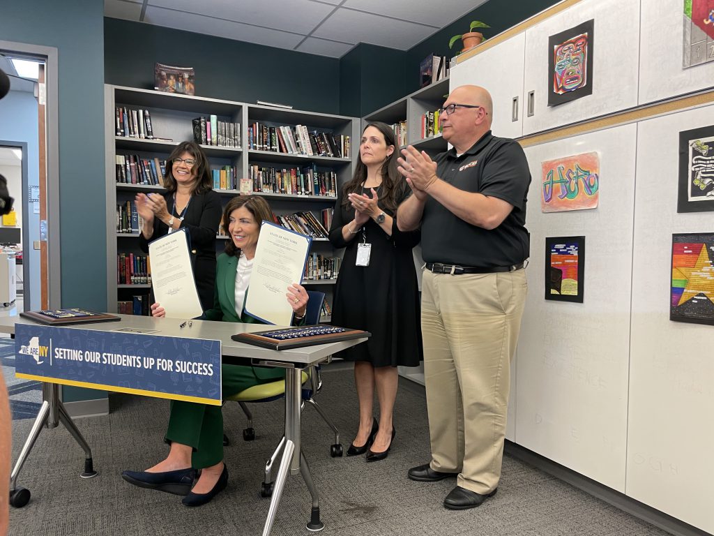 New York State Governor Kathy Hochul holds up both pieces of legislation, with Capital Region BOCES District Superintendent Lauren Gemmill and Chief Operating Officer Joseph Dragone, after signing the two bills into law during a visit to Tech Valley High School on Thursday, Sept. 7.