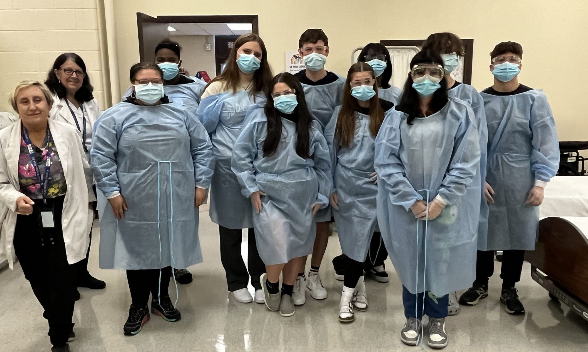 Ten students wearing smocks and surgical masks line up to pose for a picture