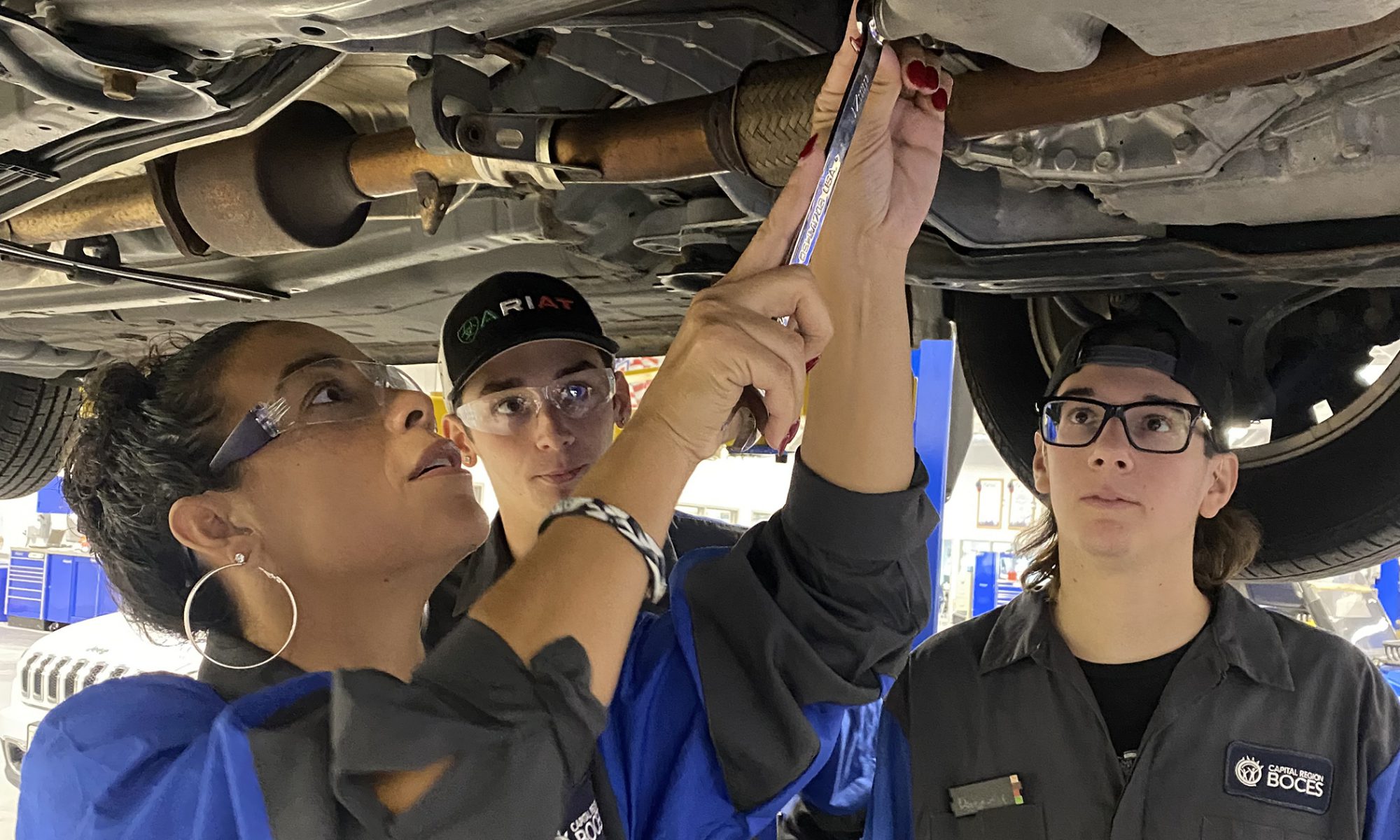 BOCES CTE students Ashton Alexson and Dominick Champagne show Principal Shelette Pleat where to dispense oil from underneath her car.