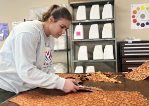 Career and Technical Education Global Fashion Studies senior Faith Coates cuts a straight line for a perfect edge on a piece of cloth for a class project. 