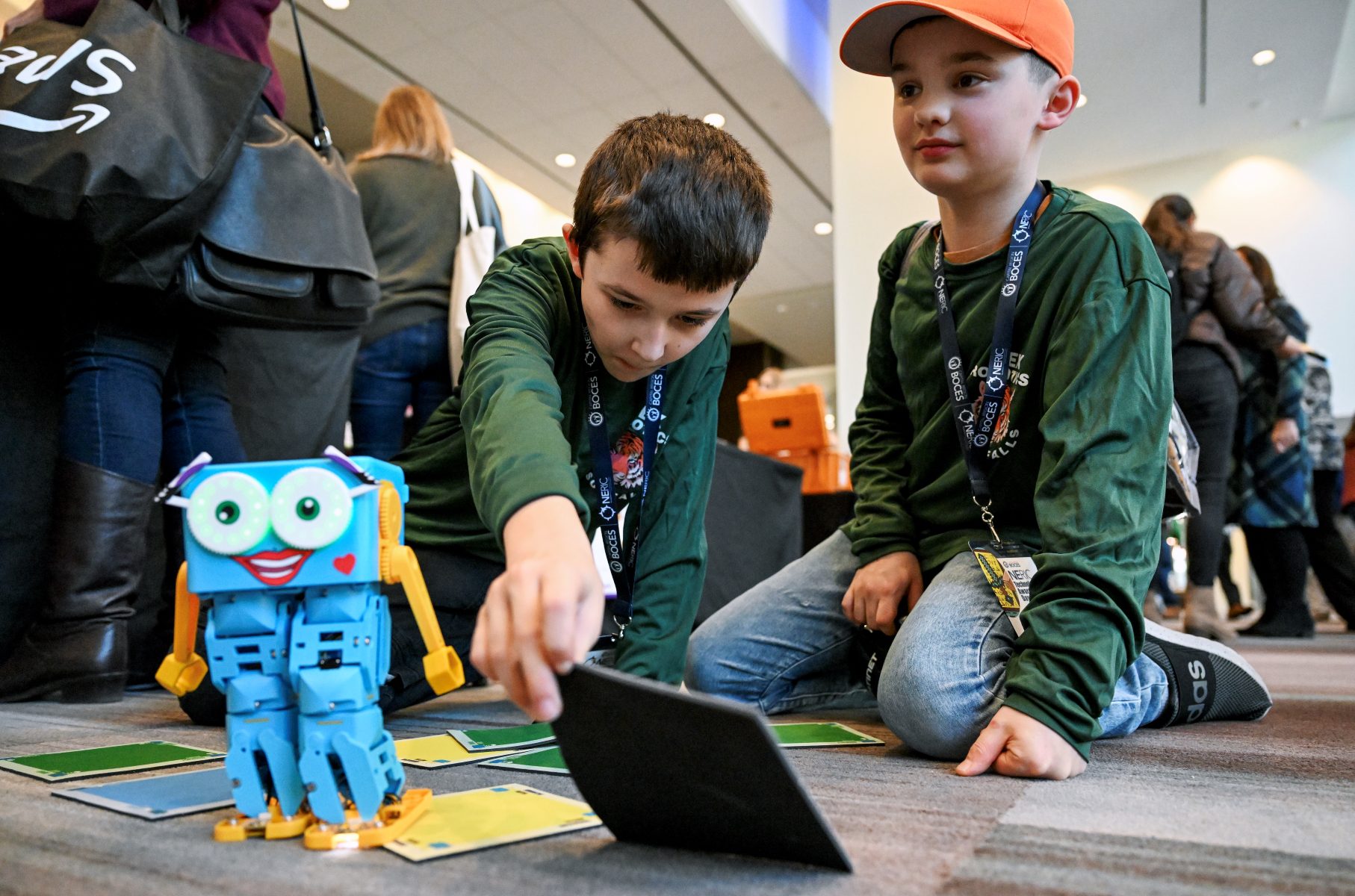 Two young boys sitting on the floor, participate in friendly technological exercise.