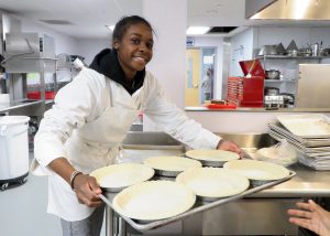 A culinary student prepares to place a tray of pie shells for the oven.