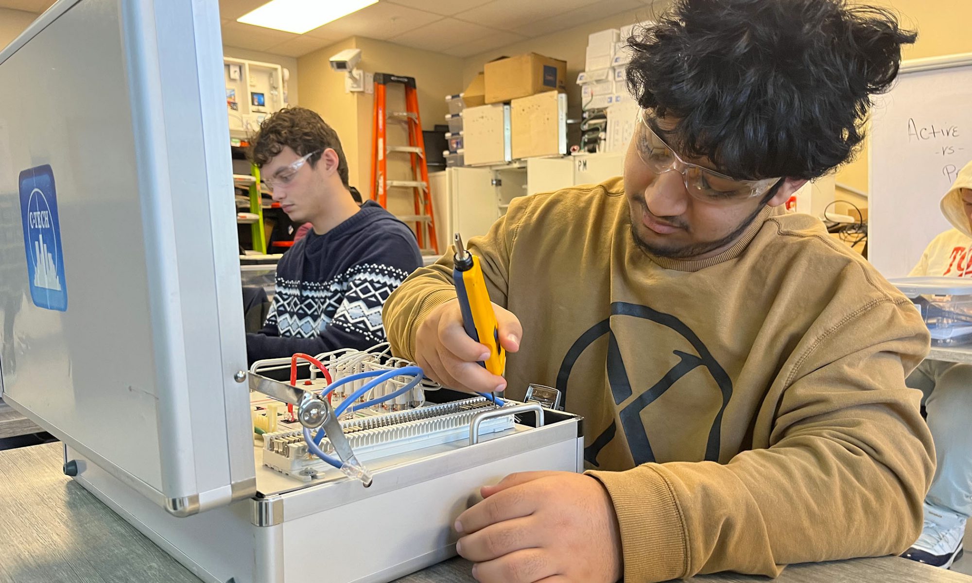 A student works on a kit that looks like a series of wires inside a briefcase during an Network Technology exercise.