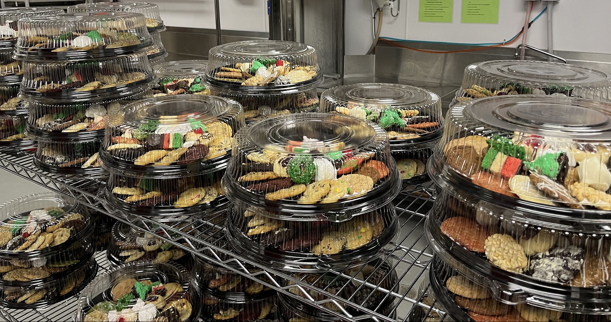 Several dozens of cookies neatly arranged on their respective plates, stand on shelves, prepared to be sold.