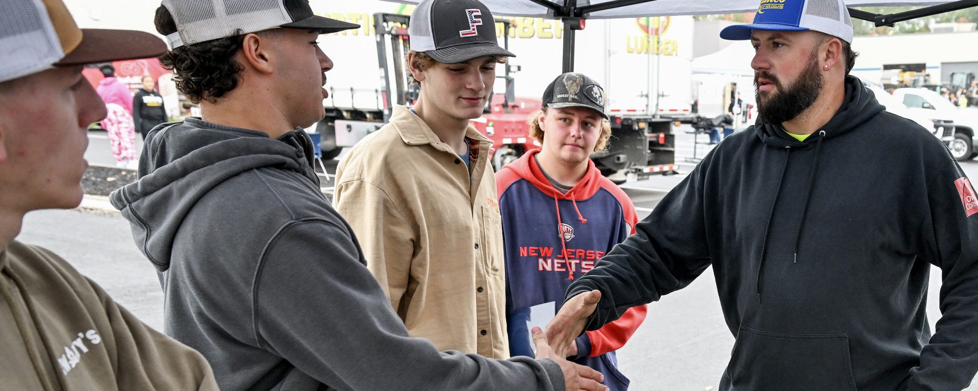 Two men square up to shake hands as three others look on.