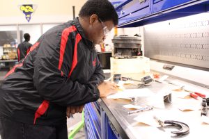 A student looms over a collection of various parts as the lay on a work bench.