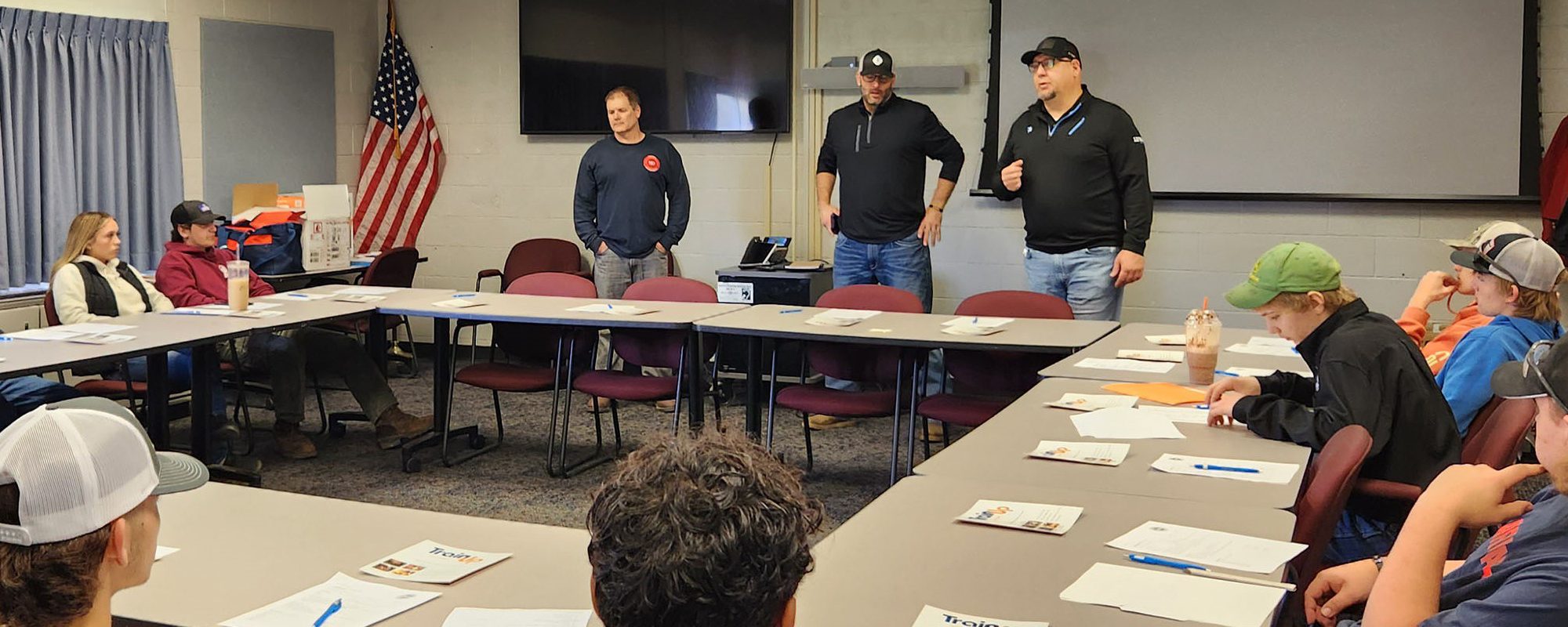 Labor representatives speak in front of a class of students.