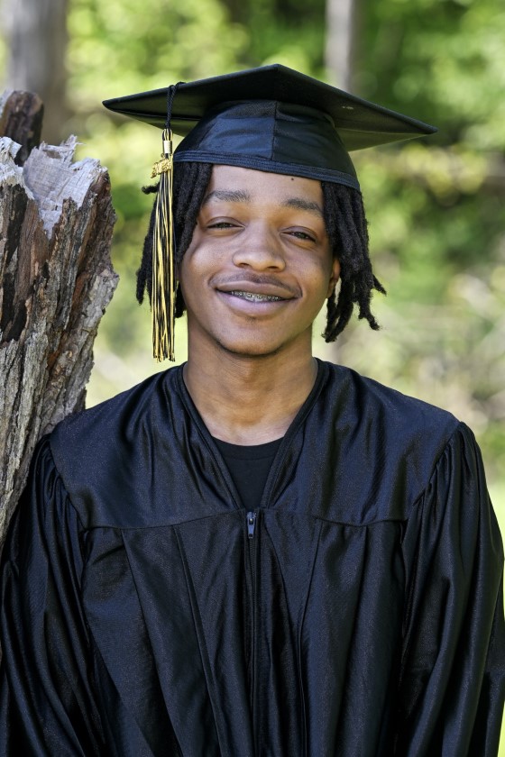 student smiles near a tree