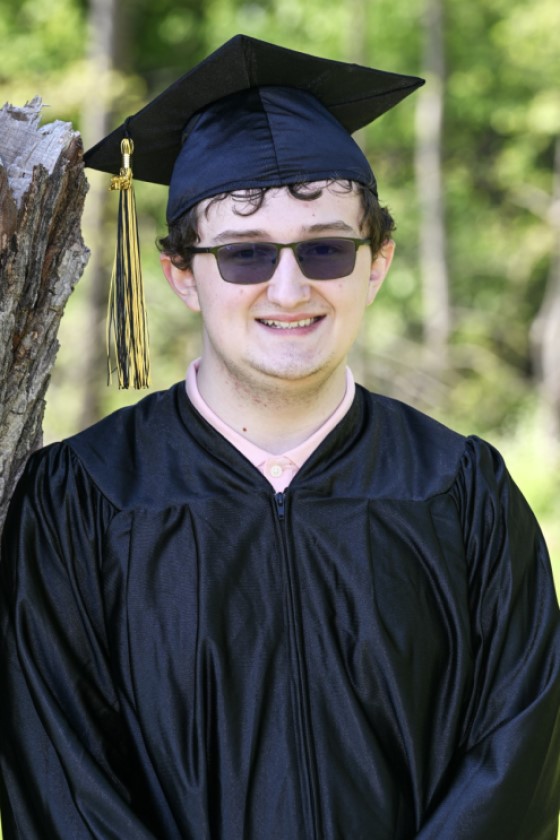 student wearing cap and gown and tinted glasses