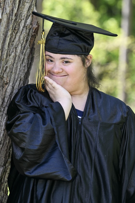 student leans against a tree
