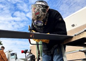 Student welds outdoors