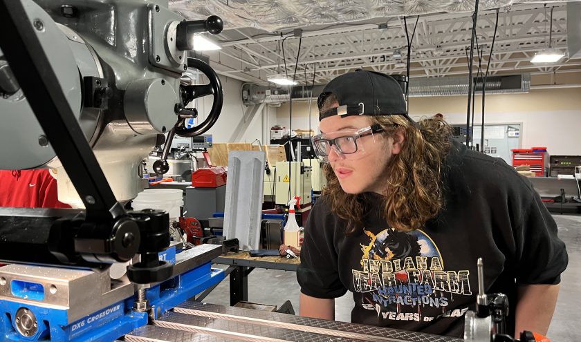 A CTE student wearing protective eyewear works on a metal project.