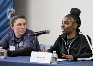 A student speaks at a table as other panelists look on