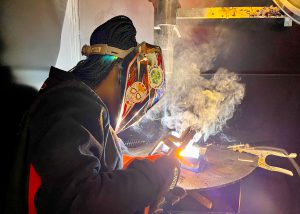 A student welds as smoke rises
