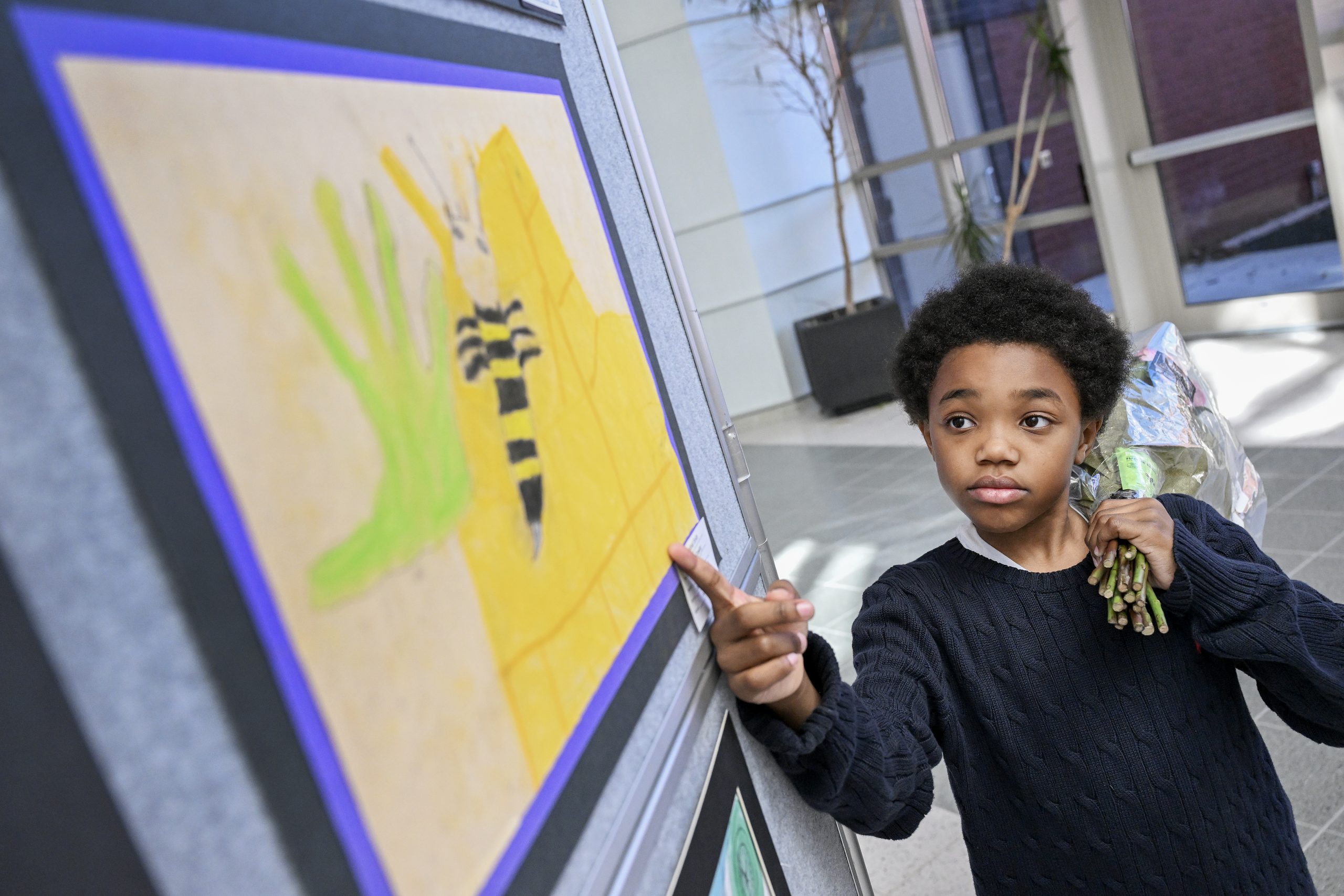 A student points at a piece of colorful artwork.
