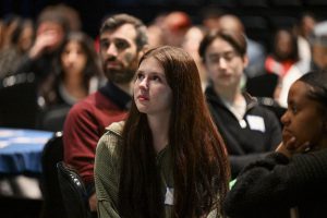 A student listens intently in a crowd.