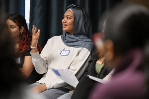 A student in a group wearing a nametag smiles and others look on.
