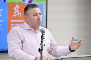 An adult speaks at a microphone.