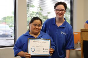 Two SELFI Program graduates stand side by side wearing their blue SELFI program shirts. 