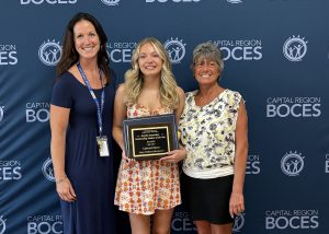 Student holds award with teacher and mom