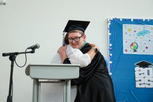 Graduate Jacob Baker hugs teacher during the June 13 Maywood graduation ceremony.