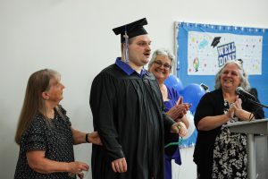 Maywood Academy graduate Joseph Toubman stands with BOCES staff.