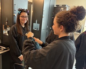 Student cuts hair while another looks on