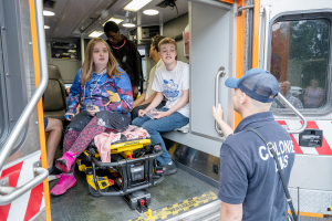Maywood Academy students sit in the back of an ambulance as a Colonie Emergency Medical Technician stands outside of the truck during Community Helpers Day.  