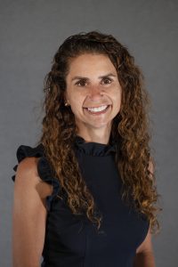 Headshot of a woman who is smiling at the camera, wearing a black, sleeveless shirt