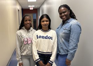 Three students pose in a hallway