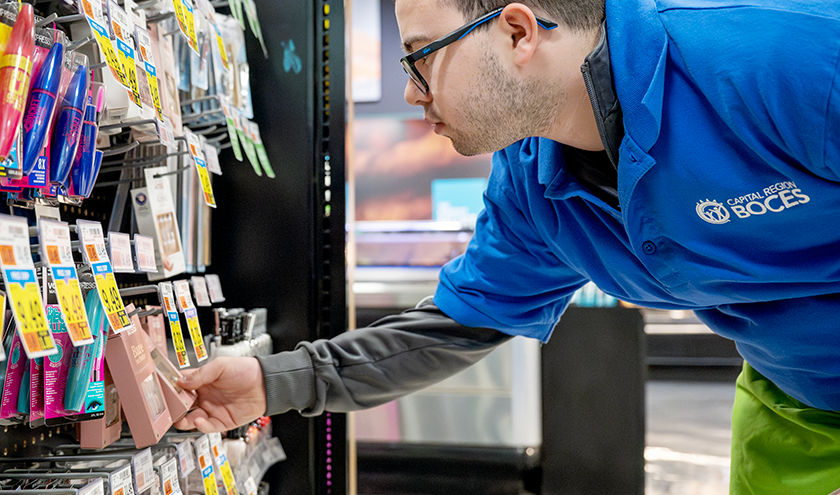 A smiling student plays on a colorful playground slide.