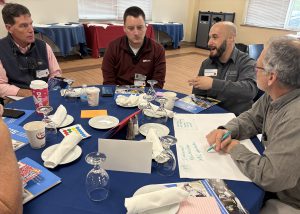 Teachers and business people speak around a table