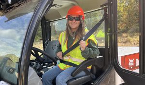 A student smiles in a piece of heavy equipment