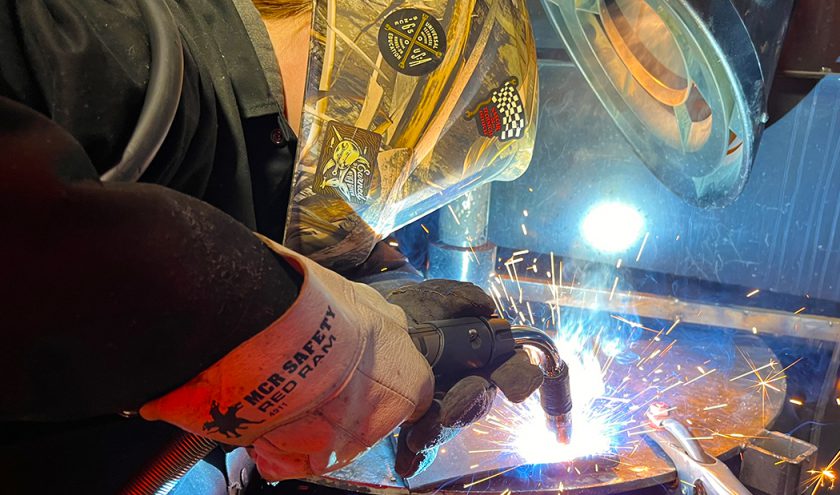 A CTE student wearing protective eyewear works on a metal project.