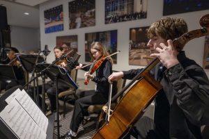 Students are seated playing musical instruments