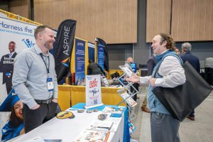 Two men are conversing at the vendor showcase at Tech A-Day