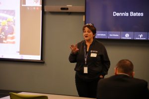 A BOCES staff member stands in front of a conference with a screen behind her as she presents to an audience.