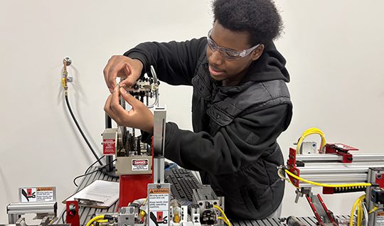 Two health careers students, one wearing a protective mask on her mouth, work on a project.