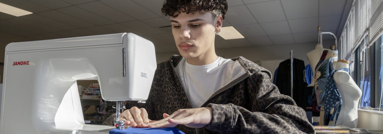 Welding students in protective clothing work together on a project.