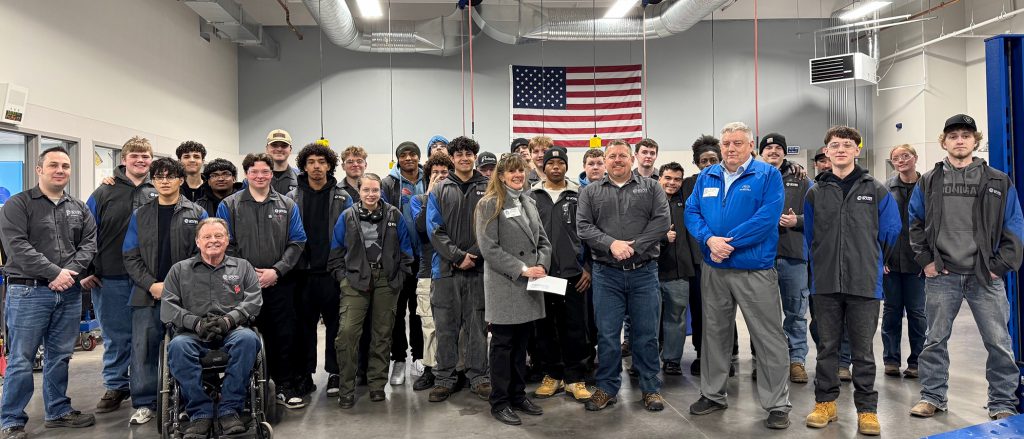 Group photo of donation with auto students in the background
