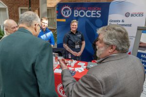 Attendees speak with staff at a Capital Region BOCES information table during an indoor networking event, with banners for Grants & Development visible behind the display.