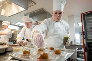 Culinary students add the finishing touches to a meal.