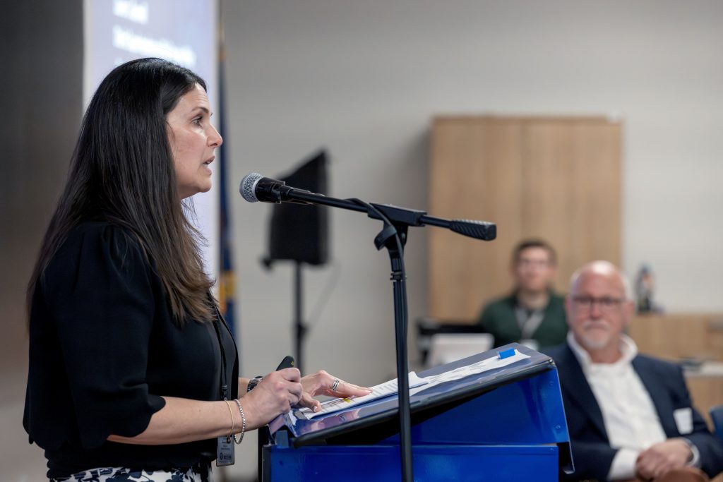 A woman speaks into a microphone at a podium
