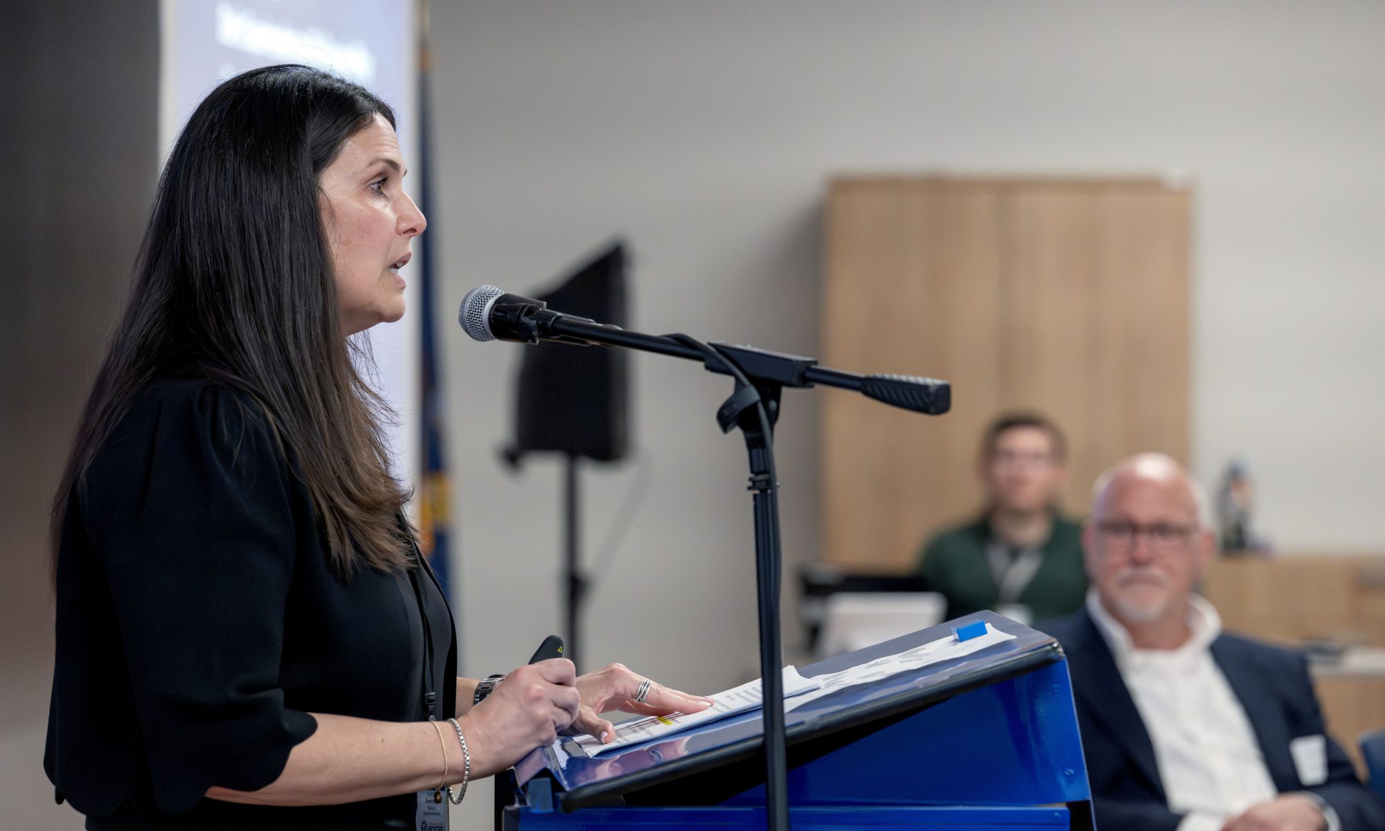 A woman speaks into a microphone at a podium