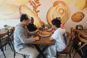 Four students from Guilderland High School are sitting at a table while they share a platter of Borek at Tuscan Bakery in Menands.