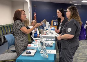 Two students talk with a recruiter over a table