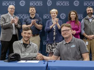 Student holds sign with business partner and digniteries 