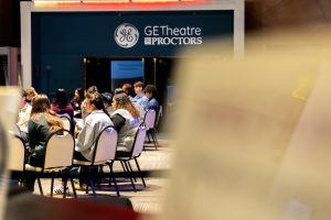 A distant photo of a student circle at the Youth Summit at Proctors Theatre. 