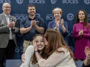 Salon owner kisses student on the cheek as student smiles